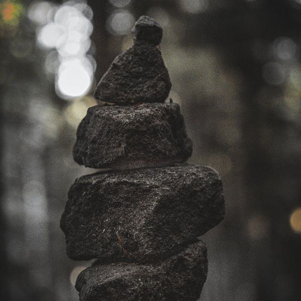 A balanced stack of dark stones on a calm surface.